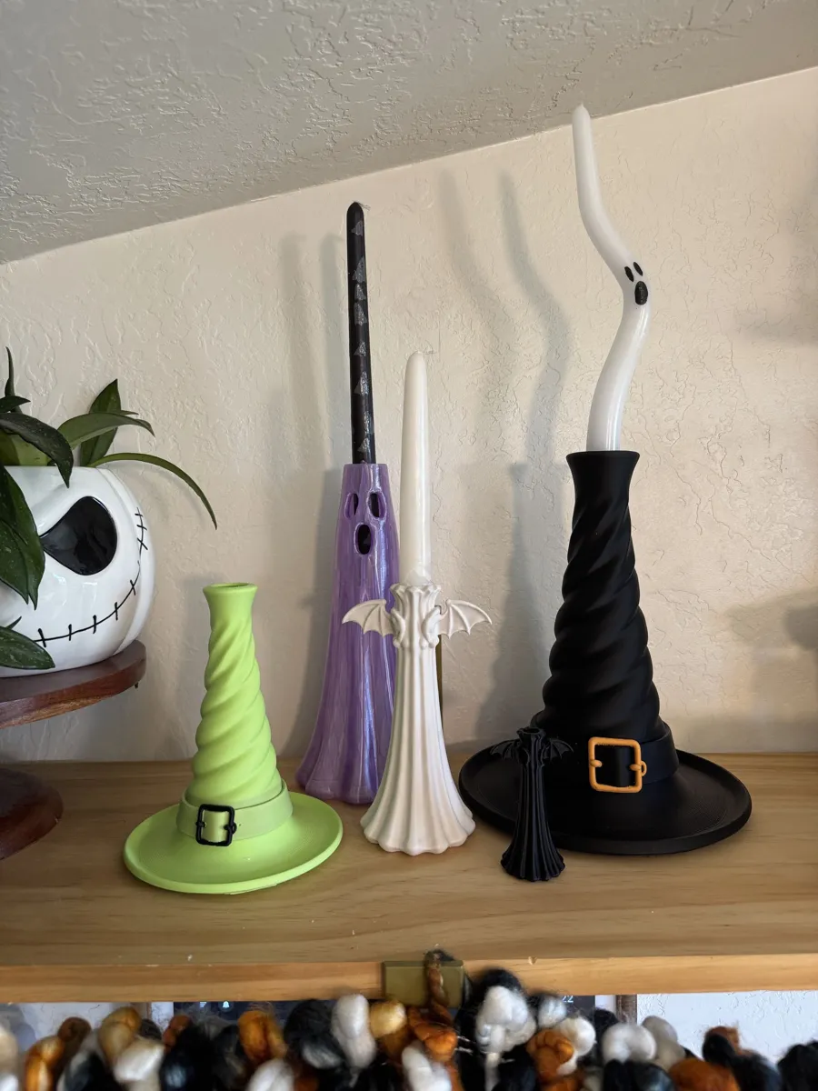 Witch hat, ghost and bat candle holders on a shelf